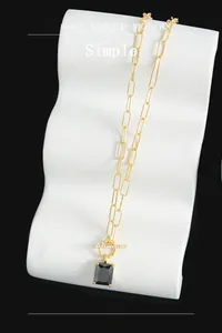 Detail of S925 silver necklace with gold rectangle chain and black gemstone pendant