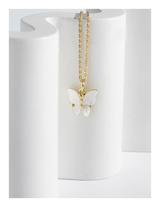 Détail d'un collier papillon doré avec pendentif en nacre blanche sur support moderne