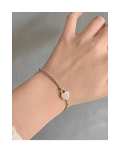 Detail of S925 sterling silver beaded bracelet with minimalist heart lock pendant on wrist