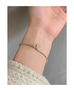 Detail of S925 sterling silver beaded bracelet with heart lock charm on female wrist