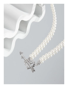 Detailed macro view of double-strand pearl necklace with silver cupid heart OT buckle