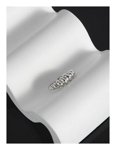 Macro shot of silver croissant dome ring displayed on a white wave art pedestal