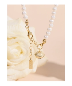 Gros plan d'un bracelet de perles S925 avec breloque cloche dorée et fermoir mousqueton