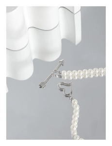 Close-up of pearl necklace featuring a silver Cupid arrow heart toggle clasp detail