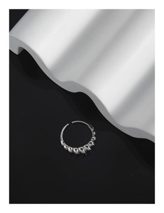 Macro detail of silver croissant ring showing twisted texture on minimalist background