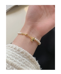 Gros plan d'un bracelet de perles S925 élégant avec clochette dorée au poignet féminin