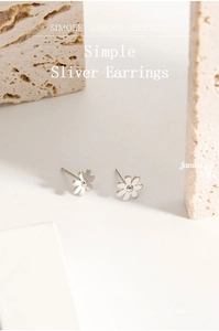 Detailed view of S925 silver daisy stud earrings on minimalist stone texture background