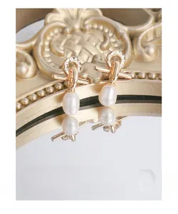 Macro view of gold cross earrings with zircon pavé and teardrop pearls on a frame