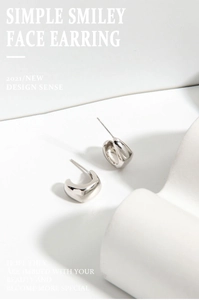 Close-up of S925 sterling silver minimalist smiling face stud earrings on geometric props