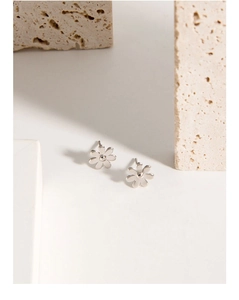 Detailed view of 925 sterling silver daisy stud earrings on minimalist stone props
