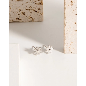 Minimalist S925 sterling silver daisy stud earrings on a textured stone background
