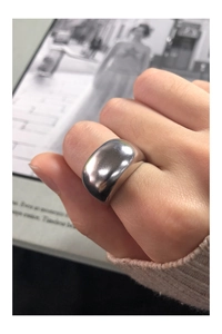 Close-up of minimalist polished silver wide band ring worn with beige knitwear