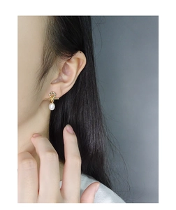 Close-up of minimalist S925 silver earrings with pavé zircon cross and white teardrop pearl