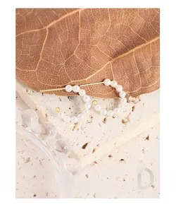 Detail of C-shaped pearl hoop earrings in S925 silver on natural stone background