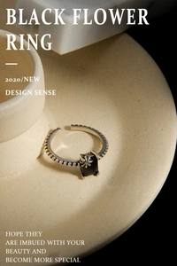 Vue macro d'une bague ajustable en argent avec fleur noire et pierre rectangulaire