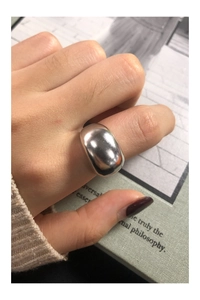 Close-up of a wide curved polished silver ring with a minimalist mirror finish on a finger