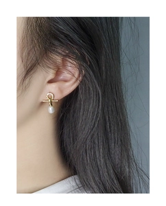 Close-up of elegant gold cross earrings with white pearls and micro-pave cubic zirconia