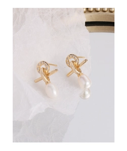 Detailed view of gold cross-knot stud earrings with pavé zircon and elegant white pearls