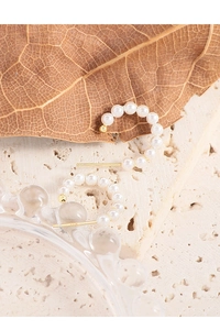 Detail of S925 sterling silver stamp on golden C-shaped hoop earrings with white pearls