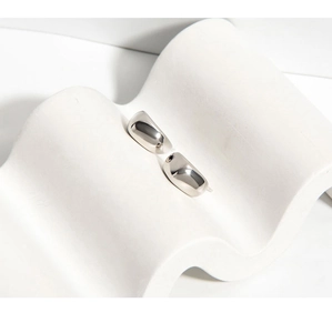 Close-up of polished minimalist water-drop S925 silver stud earrings on white stand