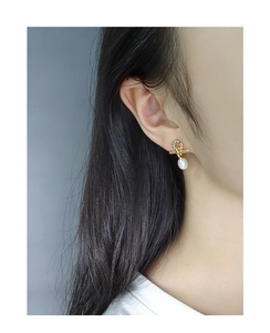 Detailed view of elegant gold drop earrings with micro-set zircon and white oval pearls