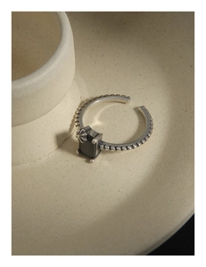 Détail macro d'une bague rétro en argent avec zircon noir et gravure florale chic
