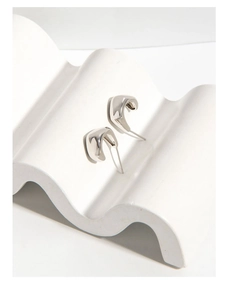 Macro shot of minimalist silver liquid metal stud earrings with high polished mirror finish