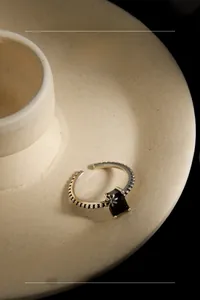 Détail d'une bague vintage en argent avec zircon noir et texture perlée florale