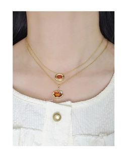Dettaglio macro della collana dorata a strati con ciondoli in pietra rossa e ambra