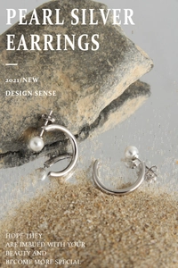 Detail of S925 sterling silver C-shaped earrings featuring a round pearl on a stone surface