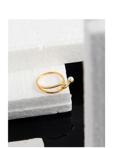 Detail view of a gold-plated crisscross silver ring with a lustrous white pearl accent