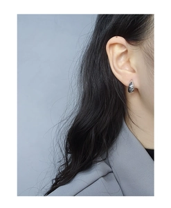 Close-up of minimalist silver teardrop earrings with a polished mirror finish on model