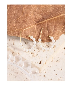Macro shot of S925 silver pearl hoop earrings on natural stone and dried leaves