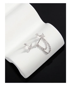 Macro shot of silver asymmetric star earrings with fine chains and shimmering zircons