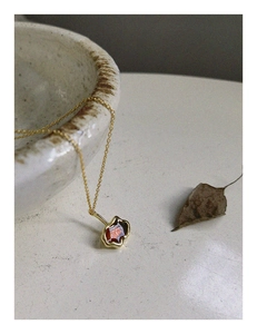 Dettaglio della collana dorata minimalista con ciondolo in pietra rossa e design vintage