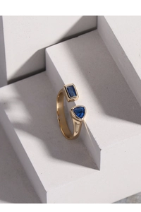 Detailed shot of open gold ring with blue rectangular and triangular zircon gemstones