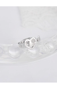 Detail of silver S925 heart belt buckle ear cuff on textured glass surface
