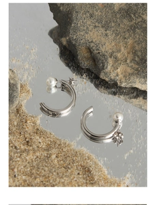 Macro detail of S925 sterling silver C-shaped hoop earrings with elegant white pearls