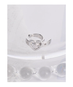 Macro shot of silver heart ear cuff with dotted texture on lace and glass background