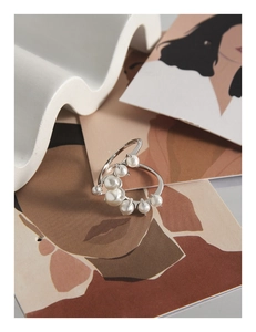 Macro shot of silver U-shaped ring with seven clustered pearls on artistic backdrop