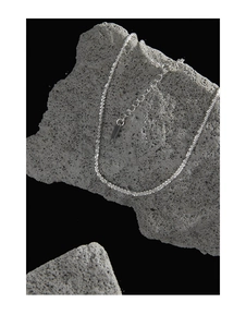 Macro shot of silver textured chain with lobster clasp and extension on a grey rock