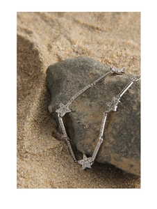 Detailed macro view of S925 silver star bracelet with zircons on natural stone and sand