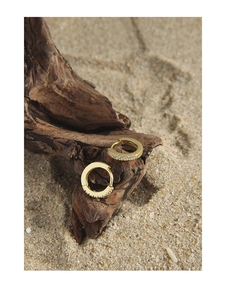 Close-up of small gold hoop earrings with zircon stones on a rustic wood background