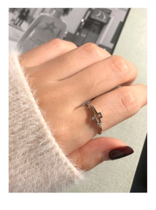 Close-up of minimalist S925 sterling silver cross ring worn on finger with soft knitwear