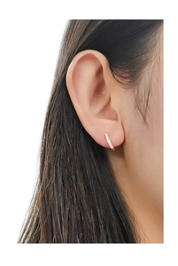 Macro detail of gold pavé huggie hoop earring with white zircons on female model ear