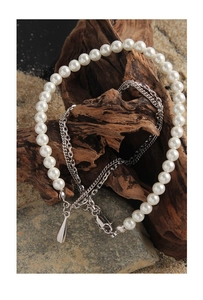 Detail view of double-layer silver necklace with pearls and teardrop pendant on stone