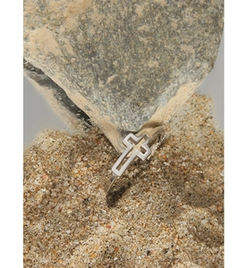 Macro detail of silver geometric cross ring placed on natural desert sand and rock