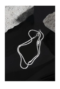 Macro shot of S925 sterling silver chain with lobster clasp on dark mirror and rough stone