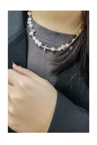 Close-up of a pearl necklace with silver butterfly pendant worn with a stylish blazer