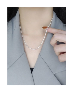 Close-up of sparkling S925 sterling silver chain on model neck in gray suit